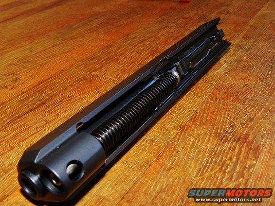 Gun slide assembly with recoil spring on wooden surface