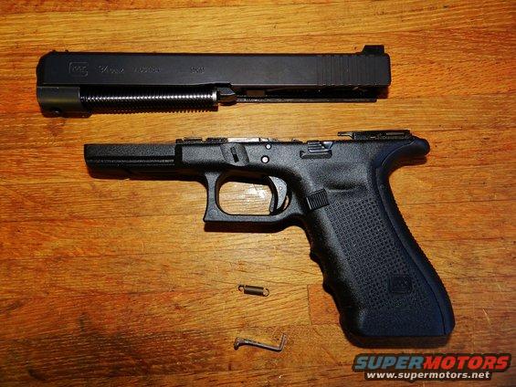 Glock pistol disassembled into slide and frame on a wooden surface