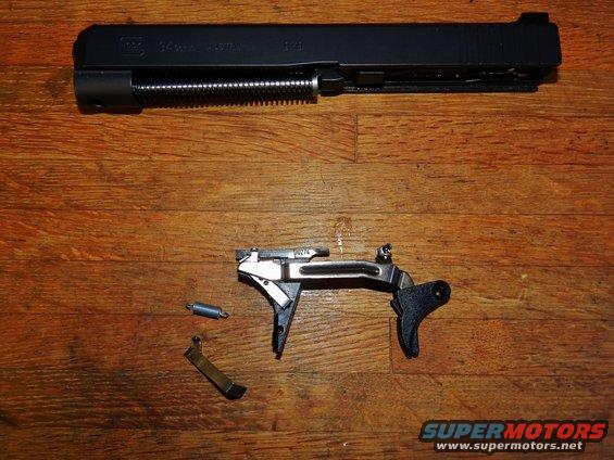 Glock pistol slide and trigger assembly disassembled on wooden surface