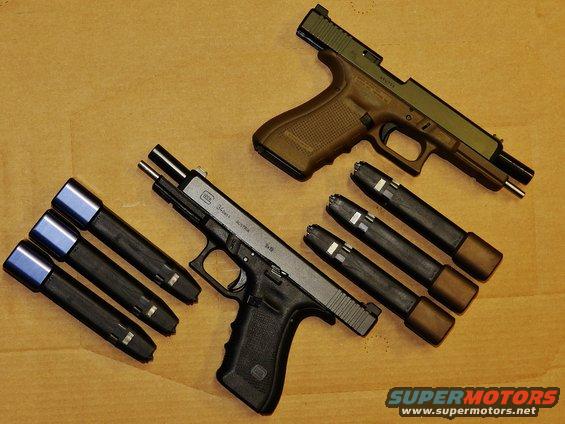 Two Glock handguns and magazines on a wooden surface. One handgun is tan and olive green, the other is black. The black handgun has 'Glock 34 Gen4 Austria' visible