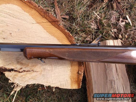Close-up of a rifle's wooden stock and barrel resting on logs