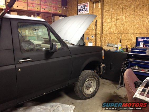 Black Ford Bronco with hood up in a garage, tools and boxes in background