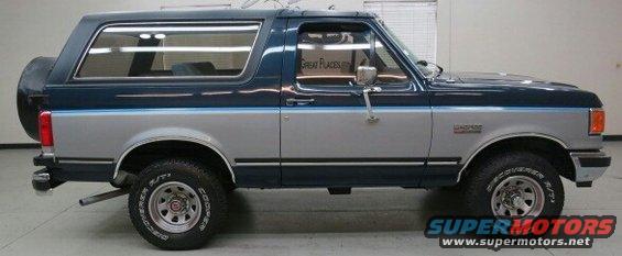 Side view of a two-tone blue and silver Ford Bronco with a spare tire on the back