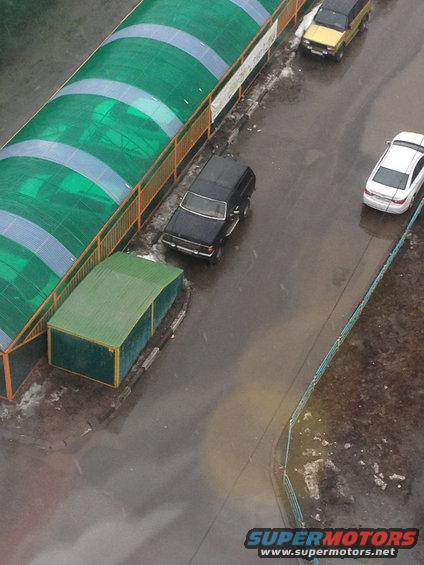 Black SUV parked on wet asphalt, side view with front quarter visible