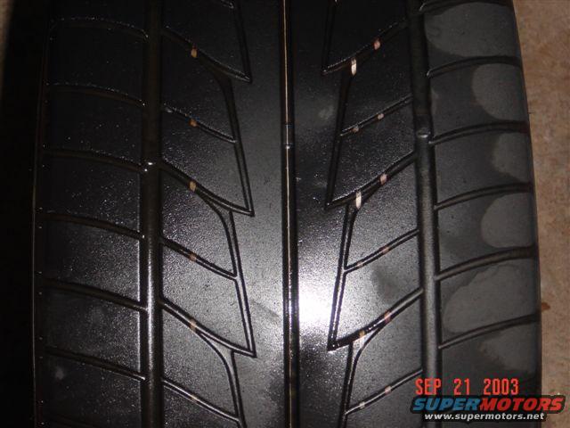 Close-up of a black tire tread with visible wear and small orange specks