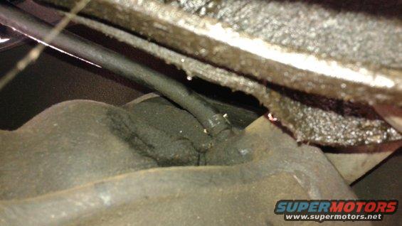 Close-up of greasy underbody mechanical parts with visible hoses and metal