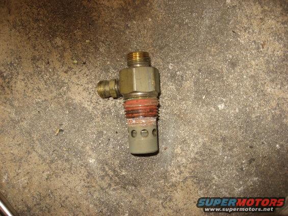 Close-up of an air compressor drain valve with brass fittings and a perforated metal end