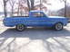 1965 Ford Ranchero - A blue 1965 Ford Ranchero pickup truck is parked on a concrete surface with trees in the background.