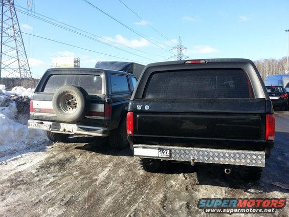 Two black Ford Broncos parked on a dirt road with snow, one with a spare tire mounted on the rear door