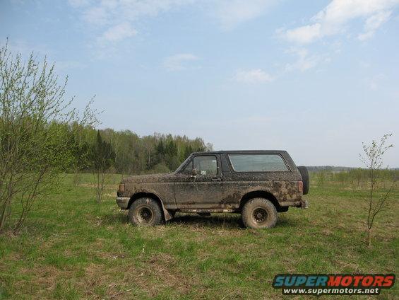 Side view of a muddy 1987 Ford Bronco in a field