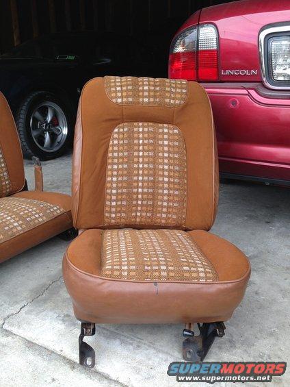 Brown plaid and vinyl car seats in front of a black car and a red Lincoln