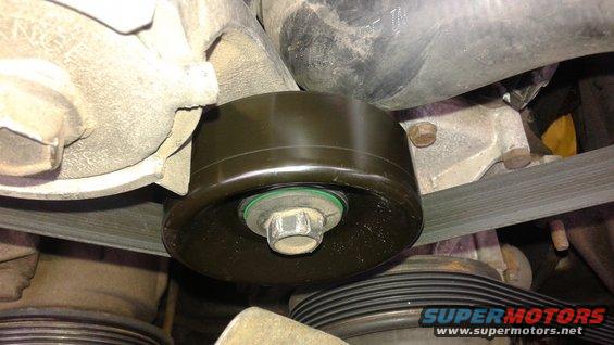 Close-up of a vehicle's engine belt and a pulley with a green seal