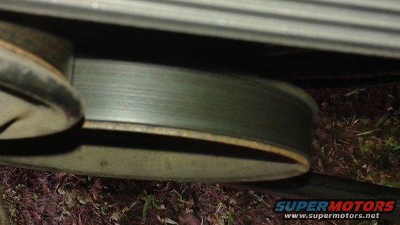 Close-up of a green pulley with a ribbed belt, part of a vehicle's engine bay