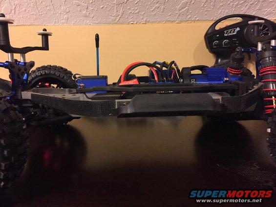 RC car chassis with blue electronics, red wires, and a remote control