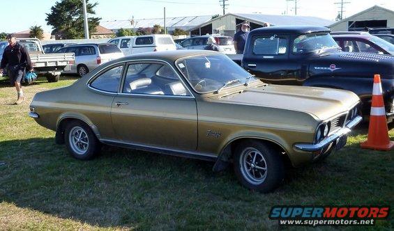 Gold coupe with a badge on the fender that reads 'Vauxhall' parked on grass