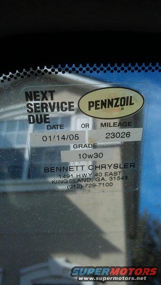 Service sticker with Pennzoil logo, next service due date 01/14/05, mileage 23026, grade 10W30, and Bennett Chrysler contact info