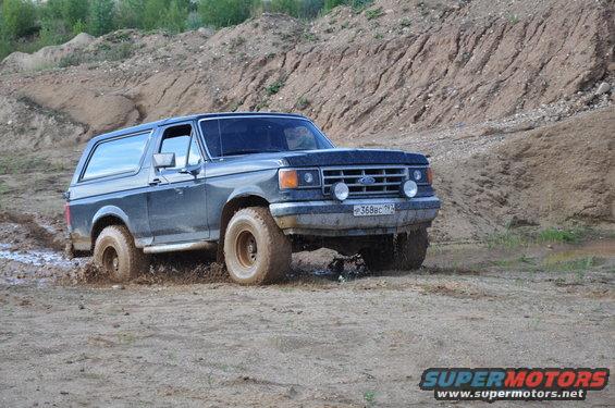 Gray 1987 Ford Bronco driving through mud