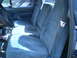 1979 Ford Bronco - The interior of a blue vehicle shows three front seats and seatbelts.