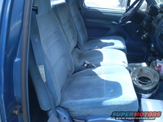 Interior view of blue cloth seats and dashboard in a truck, with a metal object on the floor