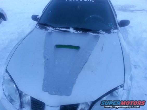 Front of a Pontiac Grand Prix covered in snow, with a green vent on the hood