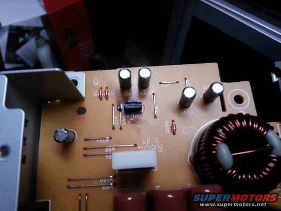 Close-up of a circuit board showing capacitors, resistors, and a toroidal inductor. Text 'R604 0.05' is visible