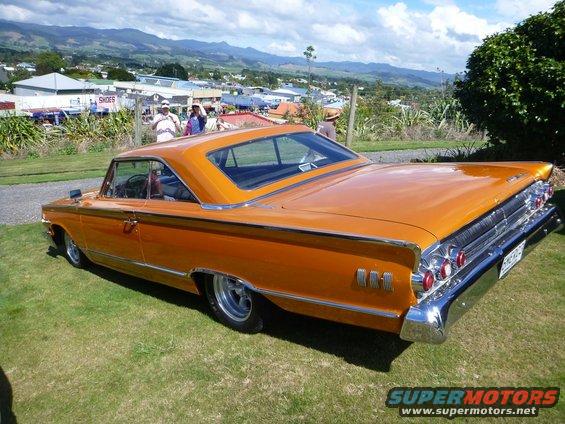 Orange coupe with chrome trim and fins, viewed from the rear three-quarter angle