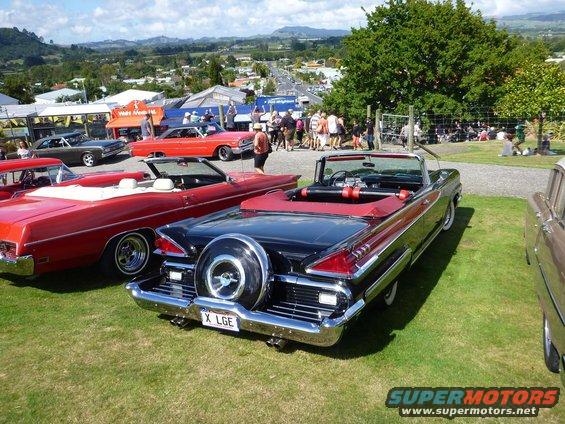 Black convertible with continental kit and red interior, rear view. License plate X LGE