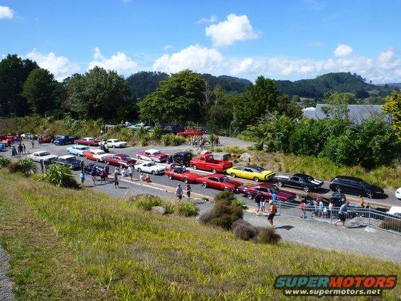 Outdoor car show with dozens of classic cars parked in rows under a blue sky with clouds