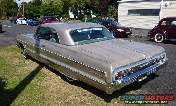 Champagne 1964 Chevrolet Impala coupe rear view, chrome bumper, quad taillights, on grass next to road