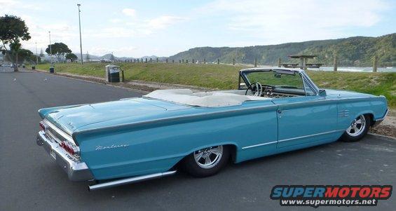 Blue convertible with white top, seen from the rear quarter