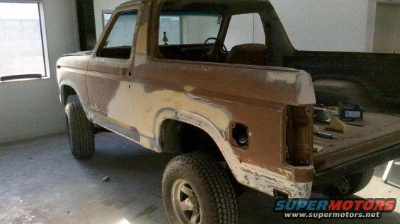 Brown Ford Bronco with body filler on the rear quarter panel and tailgate area, parked indoors