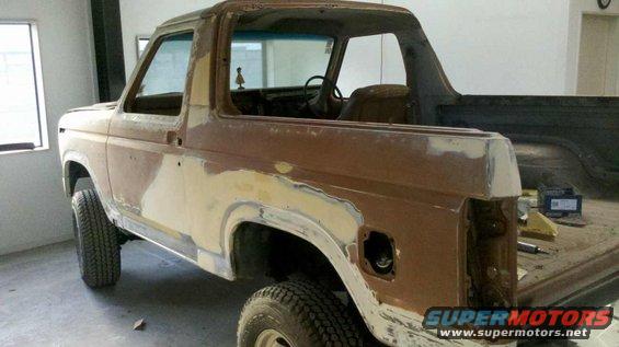 Brown Ford Bronco in body shop, undergoing repairs with visible primer and body filler