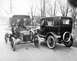 1906 Ford Model T - Two early automobiles, a touring car and a closed sedan, share the road in this vintage photograph.