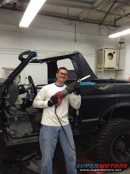 Chopped roof SUV side view with man holding reciprocating saw