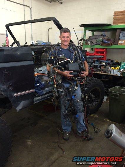 Guy in a garage holding a massive bundle of wires from a disassembled vehicle