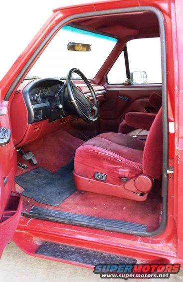 Interior view of a red truck showing the driver's seat, dashboard, and steering wheel