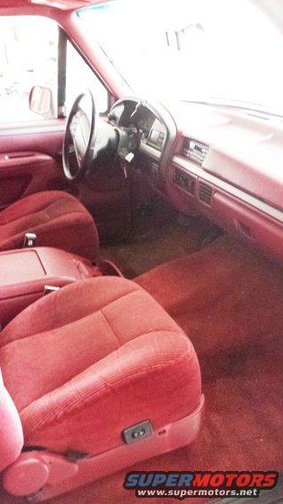 Interior view of a red truck cab, showing seats, dashboard, and steering wheel