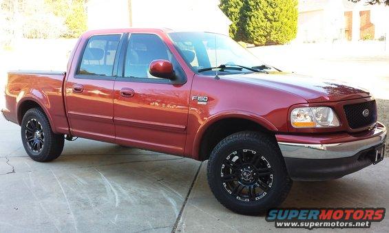 Red 2001 Ford F-150 pickup truck with black aftermarket wheels, parked on a driveway