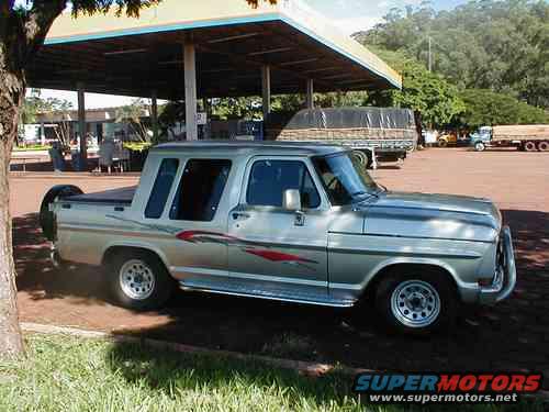 Silver 1970 Ford F-100 pickup truck with custom decals parked under a canopy