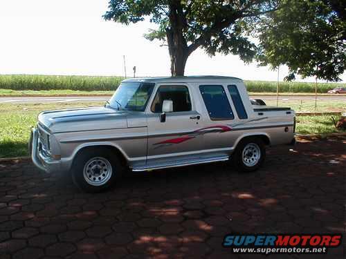Silver pickup truck with red graphics on the side, parked on a paved surface under a tree