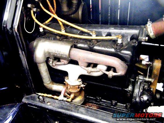 Engine of a 1915 Ford Model T with visible spark plug wires and exhaust manifold