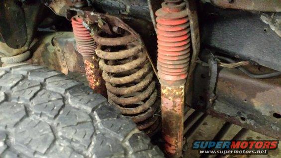 close-up of rusty suspension springs and red shocks on a vehicle frame