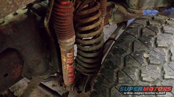 Front suspension part with red shock absorber and coil spring