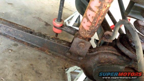 Rusty vehicle suspension with red bushings and a shock absorber