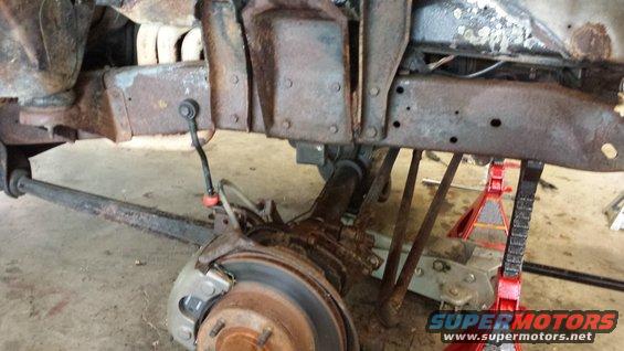 rusted vehicle frame with suspension components visible, supported by jack stands