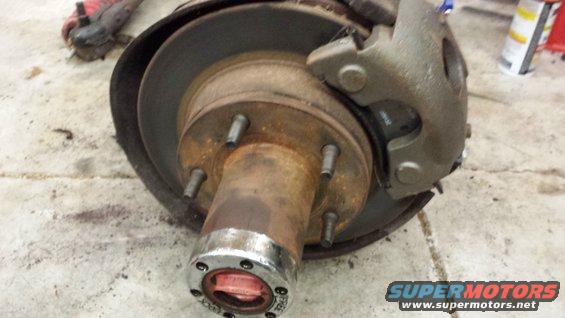 Rusty front wheel brake assembly with a chrome hubcap and red locking mechanism