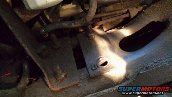 Close-up of rusty vehicle frame with hoses and bolts visible
