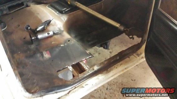 Tools on rusted interior floor pan with cut-out section and new metal patch