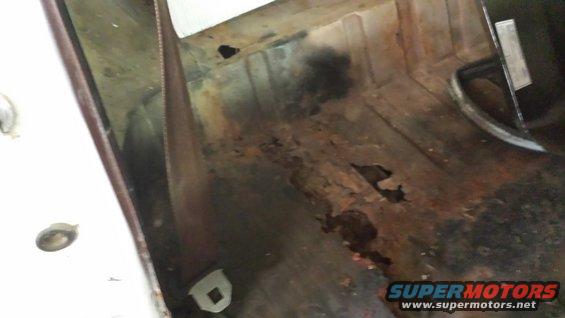 rusted out floor pan of a vehicle, showing holes and damage