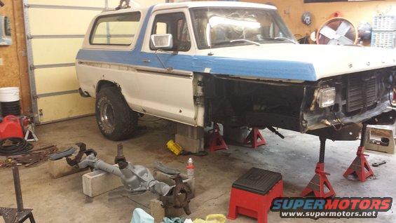 White and blue 1978 Ford Bronco on jack stands, front end disassembled